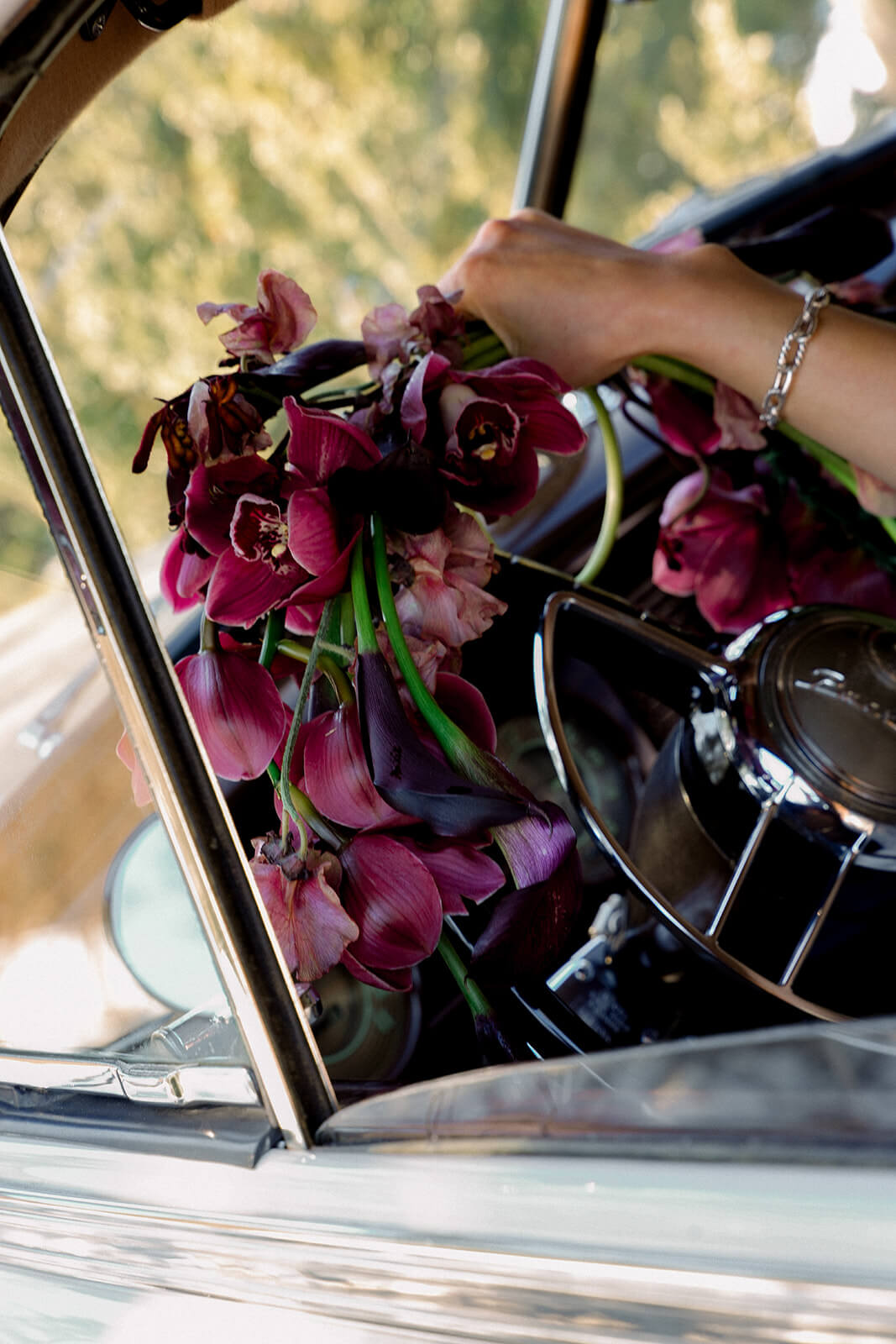 Bride holding orchid wedding bouquet through vintage Packard window — Virginia